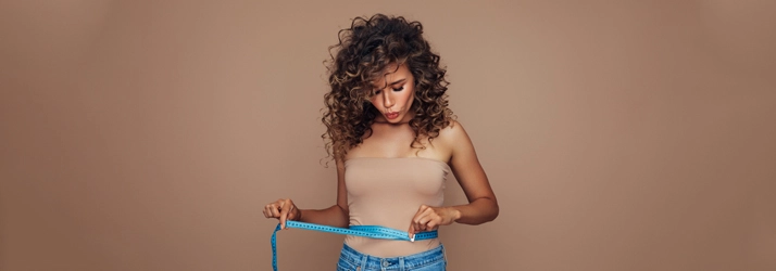 A woman measuring weight loss results on her waist