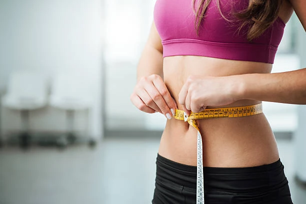 A woman using a measuring tape to measure her weight loss results